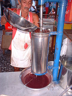 Picture of a man behind a food preparation machine outdoors.