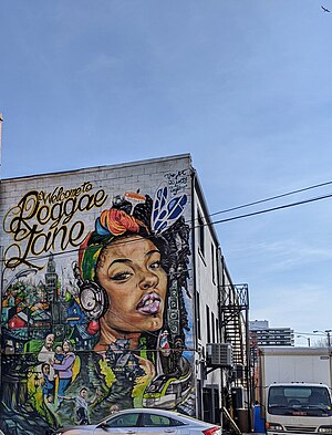 A mural depicting a young woman listening to music on headphones, a happy family and a train running through the streets of Toronto.