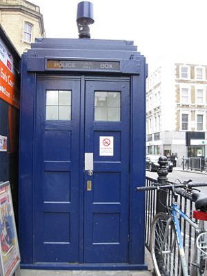 Police box mounted with a modern surveillance camera located outside Earl's Court tube station in London. The TARDIS exterior has been based on this design since the first episode of Doctor Who in 1963. The time machine is supposed to change shape to blend in with its surroundings, but the mechanism broke in the first story, and so the TARDIS has stayed like a police box ever since. In real life, the decision was made to avoid the cost of building a new TARDIS for each serial.
